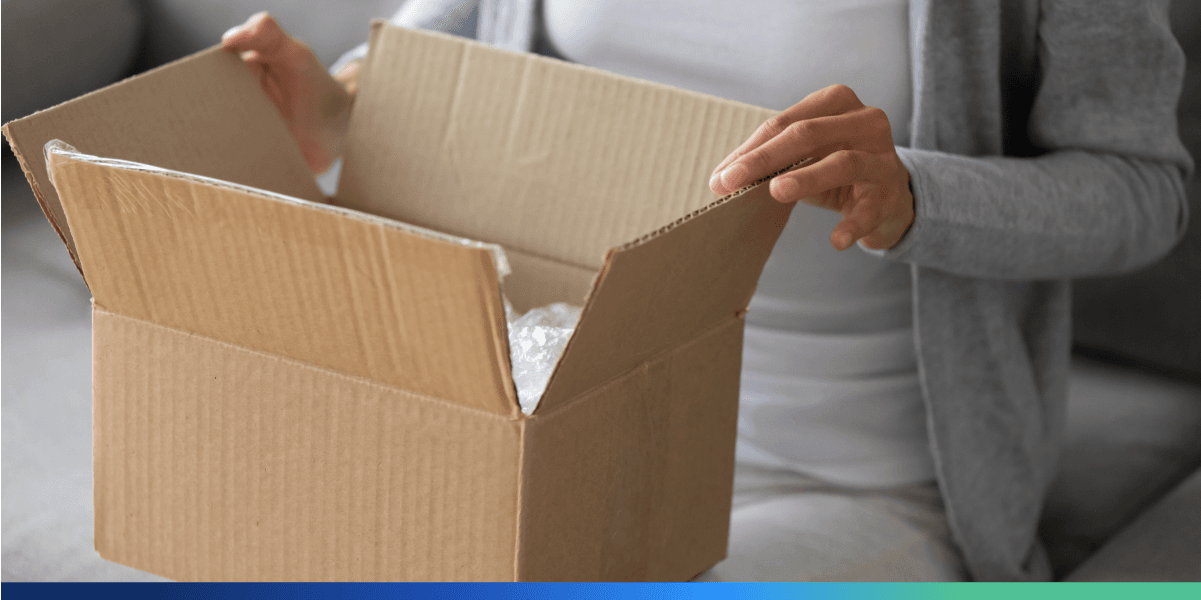 Zwrot towaru przez internet: kobieta pakuje paczkę, aby oddać zamówione rzeczy