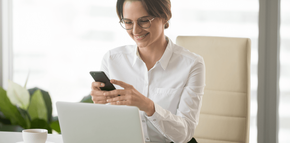 Real-time content marketing. Kobieta pracująca przy laptopie korzysta ze smartfona